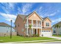 Two-story home featuring a quaint front porch, well-kept lawn, palm trees and a convenient two-car garage at 661 Black Pine Rd, Moncks Corner, SC 29461