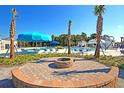 Community pool area featuring palm trees, a fire pit, sun umbrellas, and ample seating for residents' relaxation at 9712 Transplanter Cir, Ladson, SC 29456