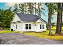 Charming white single-story home with a new roof, surrounded by lush trees and a gravel driveway at St, Saint George, SC 29477