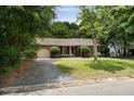 Charming brick home featuring a well-manicured lawn, mature tree, and a welcoming front porch at 1002 Sea Gull Dr, Mount Pleasant, SC 29464