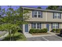 Exterior view of the tan townhouse featuring well maintained landscaping and blue doors and shutters at 1034 Lexi Ct, Ladson, SC 29456