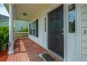 Covered front porch with brick flooring, white columns, and black front door provides a welcoming entrance to the home at 106 Brandy Ct, Summerville, SC 29485