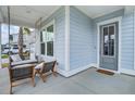 Close-up of a charming front porch with comfortable seating, a swing, and a stylish entrance door at 111 Medford St, Summerville, SC 29486