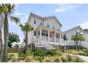 Two-story home featuring a charming porch, complemented by lush greenery and palm trees at 1494 N Lakeshore Dr, Mount Pleasant, SC 29466