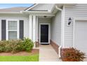 Inviting entryway with a black front door, brick accents, manicured bushes, and a charming overhead light at 158 Hayworth Rd, Summerville, SC 29486