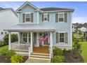 Charming light blue two-story home featuring a cozy front porch adorned with an American flag at 1832 Agate Bay Dr, Mount Pleasant, SC 29466