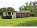 Exterior view of backyard featuring spacious lawn, deck, brick exterior, and mature trees at 2163 Pinehurst Ave, Charleston, SC 29414