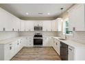 A bright kitchen featuring white cabinets, stainless steel appliances, quartz counters, and wood-look flooring at 2960 Blackfish Rd, Johns Island, SC 29455