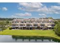 Rear view of townhomes overlooking a scenic pond, with private patios and manicured green lawns at 3588 Bagley Dr, Mount Pleasant, SC 29466