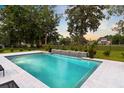 Backyard pool features a modern design with a waterfall feature, surrounded by lush landscaping and mature trees at 4246 Club Course Dr, North Charleston, SC 29420