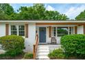 Charming white brick home featuring a cozy front porch with a blue door and well-maintained landscaping at 4939 Ashby Ave, North Charleston, SC 29405