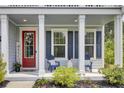 Inviting front porch with stylish seating, a charming red door, and tasteful decor, offering a cozy welcome at 5541 Alpine Dr, Summerville, SC 29483