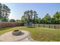 Outdoor enjoyment awaits with a paved firepit area in a spacious fenced yard with a trampoline in the background at 596 Wayton Cir, Moncks Corner, SC 29461