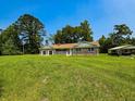Quaint brick home featuring a large front yard, detached garage, and a sunny blue sky at 840 Brittle Bank Rd, Walterboro, SC 29488
