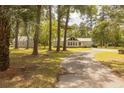 Property featuring a well-maintained lawn, a circular driveway, a house, and a matching detached garage at 1044 Academy Rd, Walterboro, SC 29488