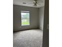 Neutral bedroom featuring plush carpet flooring, a ceiling fan, and a bright window offering a street view at 113 Lebsl Ct, Summerville, SC 29483