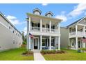 Inviting two-story home with a cozy porch, accented by an American flag and fresh landscaping at 113 Osprey Ridge Ln, Summerville, SC 29483