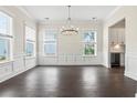 Bright dining room with large windows, dark hardwood floors, and decorative lighting fixture at 1427 Dahlia Rd, Mount Pleasant, SC 29464