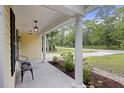 Inviting front porch with white columns, black metal chair and landscaped flower bed at 1506 Southwick Dr, Johns Island, SC 29455