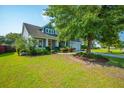 Traditional blue home featuring a well-maintained lawn, manicured bushes and vibrant green grass on a sunny day at 185 Red Leaf Blvd, Moncks Corner, SC 29461