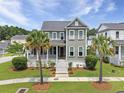 Charming two-story home featuring a covered front porch, manicured lawn, and mature palm trees at 2769 Rivertowne Pkwy, Mount Pleasant, SC 29466