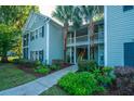 Inviting exterior view of a condo with lush landscaping and charming curb appeal with two palm trees in the center at 401 S Elgin Ct # 401, Charleston, SC 29414