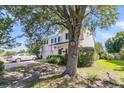 Side view of two-story home with black shutters, showcasing a lush yard and mature tree at 67 Regency Oaks Dr, Summerville, SC 29485