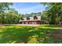 A three-car garage with an upper level, framed by a verdant forest at 6840 Early Jersey Rd, Meggett, SC 29449