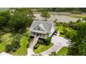 Aerial view of a two-story home with covered porch and a waterfront lot at 8964 Palmetto Rd, Edisto Island, SC 29438