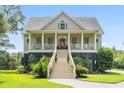 Two-story home with a covered porch, stairs, and a manicured lawn at 8964 Palmetto Rd, Edisto Island, SC 29438