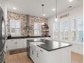 Modern kitchen features a brick accent wall, white cabinetry, and a large center island at 115 Winding Branch Dr, Summerville, SC 29486