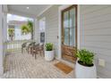 Charming front porch with brick flooring, seating, potted plants, and a decorative wooden door at 1535 Low Pk St, Mount Pleasant, SC 29464