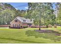 Beautiful brick home featuring lush green lawn, mature shade trees, and a side-entry driveway at 213 Turtle Point Rd, Summerville, SC 29483