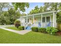 Charming home with a cheerful yellow door, inviting covered porch with blue accents, and manicured landscaping at 2343 Herndon Dr, Charleston, SC 29414