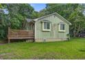 Side view of cottage-style home with wooden deck, green lawn and mature trees at 2702 Decatur St, North Charleston, SC 29405