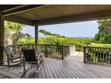 Charming covered balcony with rocking chairs offers a tranquil view of the lush surroundings and ocean at 3560 Shipwatch Rd, Kiawah Island, SC 29455