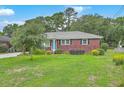 Quaint brick home featuring a well-manicured lawn and a vibrant blue front door at 4729 Lang Ridge Dr, North Charleston, SC 29405