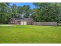 View of the rear of the brick home with an expansive grassy lawn and mature trees at 110 Terry Ave, Summerville, SC 29485