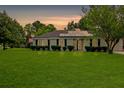 Charming single-story home with solar panels, lush lawn and manicured shrubs at dusk at 1101 Stuart Dr, Moncks Corner, SC 29461