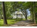 Charming home with classic architectural details, mature trees, and a welcoming fence-lined gravel driveway at 1193 River Rd, Johns Island, SC 29455