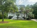 Beautiful two-story home featuring a wrap-around porch, staircase entry, and expansive green front lawn at 1447 Headquarters Plantation Dr, Johns Island, SC 29455
