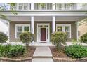 Inviting front porch featuring classic columns, manicured bushes, and an elegant entrance with a red door at 1523 Nautical Chart Dr, Charleston, SC 29414