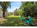 Relaxing backyard space with a fire pit and Adirondack chairs, surrounded by lush greenery and mature trees at 1625 Teal Marsh Rd, Charleston, SC 29412
