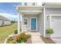 Inviting front porch featuring a rocking chair, blue front door, and decorative flower garden at 209 Parkwood Vista Way, Summerville, SC 29486