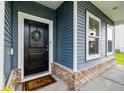 Inviting entryway featuring black door, decorative wreath, brick accents, and 'M' monogrammed welcome mat at 3010 Grinnell St, Johns Island, SC 29455