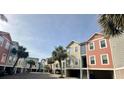 Street view of colorful townhomes with ground-level parking and lush palm trees, creating a relaxed and inviting community vibe at 81 Sandbar Ln # 28, Folly Beach, SC 29439