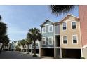 Street view showcasing colorful townhome exteriors and mature palm trees, offering picturesque curb appeal in a coastal community at 81 Sandbar Ln # 28, Folly Beach, SC 29439