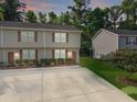 Two-story tan townhome with a long driveway, complemented by manicured landscaping and lush green trees at 1069 Lexi Ct, Ladson, SC 29456