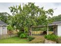 Large backyard with mature trees, a covered patio area, and a quaint picket fence at 1121 Armstrong Ave, Charleston, SC 29407