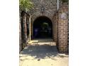 Gated entrance to a brick townhouse featuring an arched entrance with an intricate black iron gate at 128 Queen St, Charleston, SC 29401